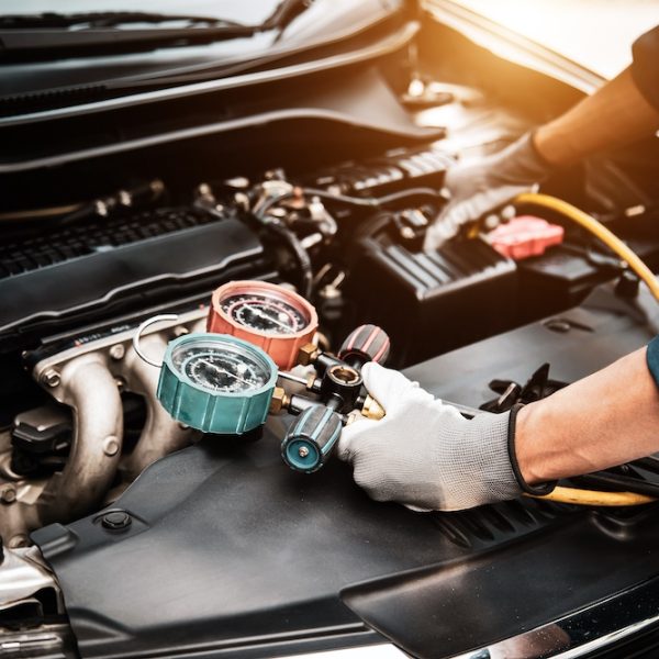 Close up hand of auto mechanic using measuring manifold gauge check the refrigerant and filling car air conditioner for fix and checking for repair service support maintenance and car insurance.